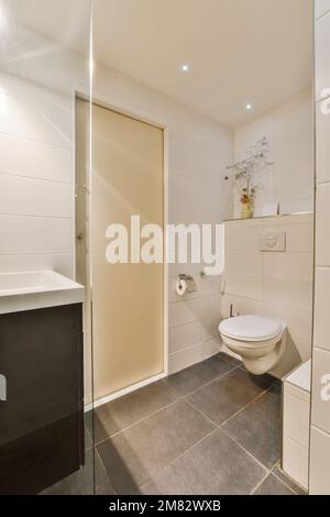 Ein kleines Bad mit weißen Fliesen und grünen Zierleisten an den Wänden,  zusammen mit einer Toilette in der Ecke neben dem Waschbecken  Stockfotografie - Alamy