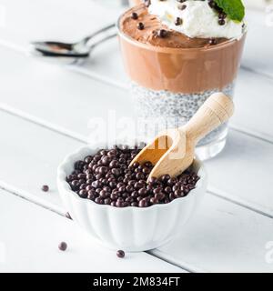 Mit Schokolade überzogene Quinoa-Puffs in einer kleinen Schüssel mit einem Holzlöffel. Stockfoto