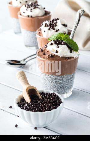 Schokoladen-Chia-Pudding-Parfaits mit einer Schüssel Schokoladen-Quinoa-Puffs davor. Stockfoto