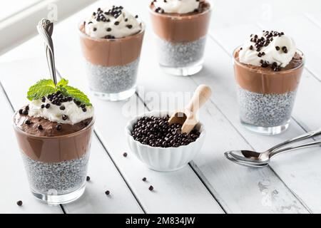Gesunde, dunkle Schokoladenmousse Chia Pudding Snacks vor einem hellen Fenster. Stockfoto