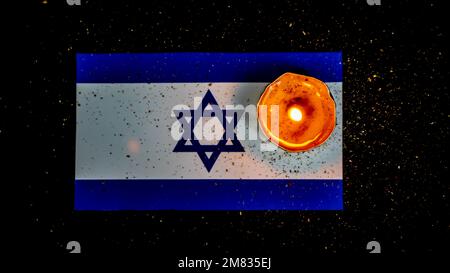 Israelische Flagge und brennende Kerzen darüber, Holocaust-Gedenktag Stockfoto