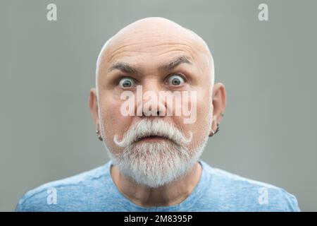 Überraschtes Gesicht eines alten erwachsenen Mannes. Nahaufnahmen eines alten, reifen Seniorenmannes mit grauem Bart isoliert auf Studiohintergrund. Emotionen Gesichter. Stockfoto