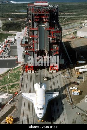 Ein Blick von oben auf das Space Shuttle Enterprise, das sich in Richtung Shuttle-Montagegebäude im Space Launch Complex Six bewegt, an Bord seines speziell konstruierten 76-Rad-Transporters. Im Hintergrund befinden sich der Umstellungsraum für die Nutzlast und der Vorbereitungsraum für die Nutzlast. Basis: Luftwaffenstützpunkt Vandenberg Bundesstaat: Kalifornien (CA) Land: Vereinigte Staaten von Amerika (USA) Stockfoto