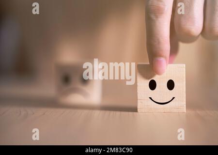 Geschäftsmann wählt ein Lächeln Emoticon Symbole Gesicht glücklich Symbol auf Holzblock , Dienstleistungen und Kundenzufriedenheit Umfragekonzept Stockfoto