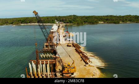 Hammer des Stapellaufers in Aktion. Baubrücke über die Meeresbucht auf der tropischen Insel Siargao. Stockfoto