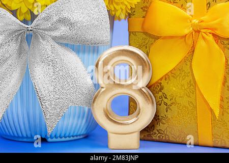 Goldene Zahl 8 mit glänzender gelber Geschenkbox und Blume in blauem Topf und silberner Schleife. Internationaler Frauentag, 8. März, Geburtstag Stockfoto