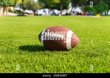 Ball für American Football auf einem Rasenplatz. Nahaufnahme mit unscharfem Hintergrund. Stockfoto