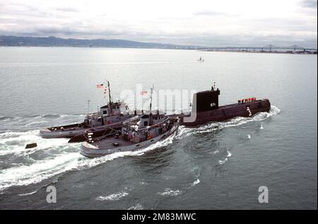 Steuerbord-Viertelansicht des nuklearbetriebenen Angriffs-U-Boots Ex-USS NAUTILUS (SSN 571), das von den großen Hafenschleudern SKENANDOA (YTB 835), Right und PUSHMATAHA (YTB 830) gezogen wird. Das NAUTILUS ist auf dem Weg zur Naval Station Treasure Island, wo es vom Flottenschlepper USS QUAPAW (ATF 110) abgeholt und nach Groton, Connecticut, gezogen wird. Basis: San Francisco Staat: Kalifornien (CA) Land: Vereinigte Staaten von Amerika (USA) Stockfoto
