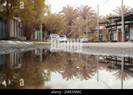 Stagnierende Wasserszene nach Regen in der vorstädtischen Asphaltstraße Stockfoto