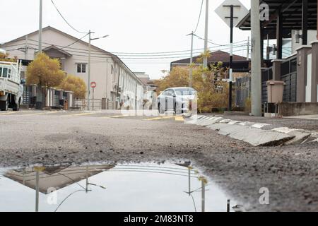 Stagnierende Wasserszene nach Regen in der vorstädtischen Asphaltstraße Stockfoto