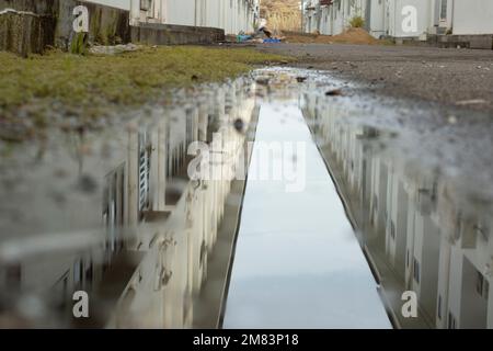 Stagnierende Wasserszene nach Regen in der vorstädtischen Asphaltstraße Stockfoto