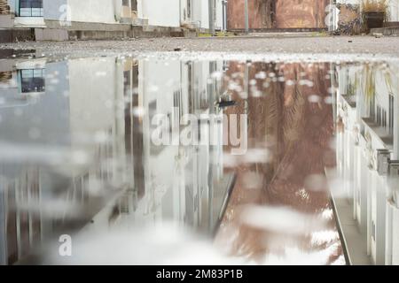 Stagnierende Wasserszene nach Regen in der vorstädtischen Asphaltstraße Stockfoto