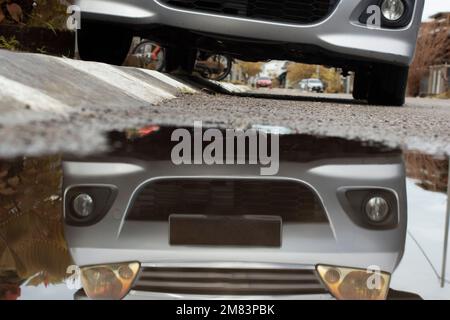 Stagnierende Wasserszene nach Regen in der vorstädtischen Asphaltstraße Stockfoto