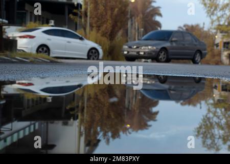 Stagnierende Wasserszene nach Regen in der vorstädtischen Asphaltstraße Stockfoto