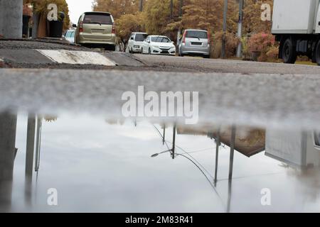 Stagnierende Wasserszene nach Regen in der vorstädtischen Asphaltstraße Stockfoto