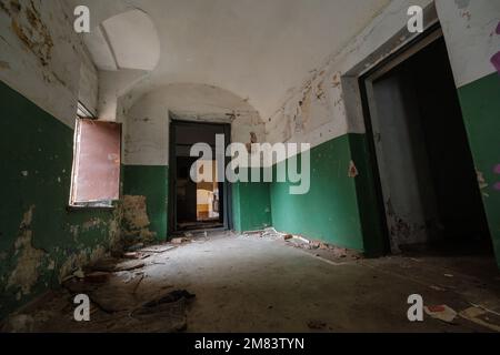 Sonnendurchfluteter Flur mit geöffneten Türen und Fenstern an den verwitterten Wänden im einsamen Gebäude Stockfoto