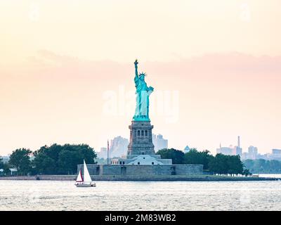 Die Freiheitsstatue von der Upper Bay in New York City, USA, während des pinkfarbenen Sonnenuntergangs Stockfoto