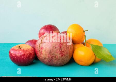 Granatäpfel, Äpfel und Mandarinen auf türkisfarbenem Hintergrund. Reife Früchte. Stockfoto