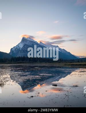 Mount Rundle spiegelte sich bei Sonnenaufgang in den Vermilion Lakes wider. Banff. Kanadische Rocky Mountains. Vertikales Format. Stockfoto