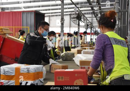 QIANDONGNAN, CHINA - 12. JANUAR 2023 - Arbeiter sortieren Lieferungen in einem Lieferzentrum in einem Logistikpark in Kaili, Qiandongnan Miao Stockfoto