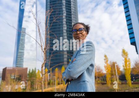 Eine Geschäftsfrau mit Brille, die in einem Gewerbepark steht und die Arme gekreuzt hat Stockfoto