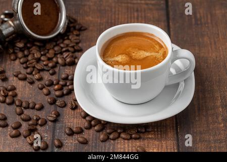 Frischer doppelter Espresso und Kaffeebohnen auf Holztisch Stockfoto