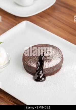 Schokoladensoufflé mit fließender Schokolade auf einem weißen Porzellanteller Stockfoto