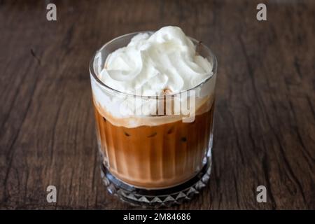 Glas mit Eismocha und Schlagsahne. Kaltes Kaffeegetränk auf braunem Hintergrund. Stockfoto