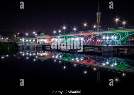 Tees Barrage Bridge on the River Tees in Stockton-on-Tees, Long Exposure Image, aufgenommen bei Nacht und beleuchtet mit rotem und grünem Licht mit Reflexion Stockfoto