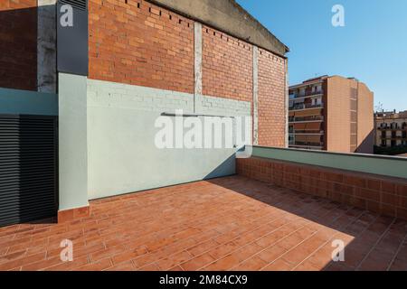 Eine leere geräumige Terrasse im zweiten Stock eines großen Hauses mit einem roten Ziegelboden zum Entspannen an warmen Sommerabenden in der Sonne des Vorbeiflugs Stockfoto