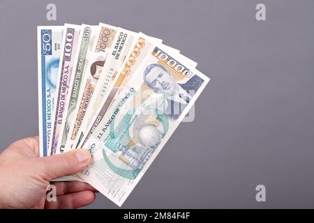 Altes mexikanisches Geld - Pesos in der Hand auf grauem Hintergrund Stockfoto