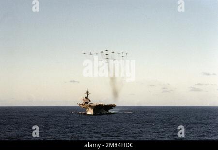 Eine Bogenansicht des Flugzeugträgers USS KITTY HAWK (CV-63), da verschiedene Luftfahrzeuge, die Carrier Air Wing (CVW-9) zugewiesen sind, in Formation über das Schiff fliegen. Land: Pazifik (POC) Stockfoto