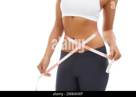 Perfekt, so wie sie ist. Eine junge Frau misst ihre schlanke Taille und zeichnet ihren Gewichtsverlust auf. Stockfoto