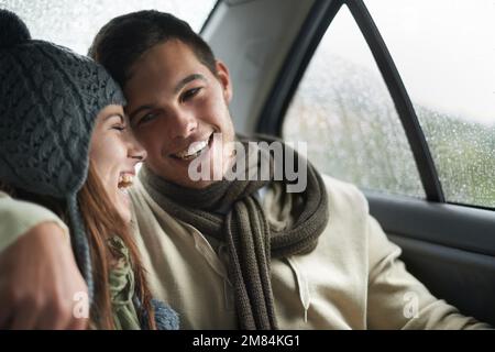 Von Liebe erwärmt. Ein junges Paar sitzt in ihrem Auto, während es regnet. Stockfoto