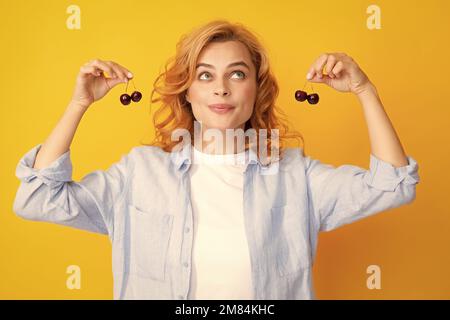 Porträt der Schönheit rötete Frau mit Kirschen auf gelb isolierten Hintergrund. Stockfoto