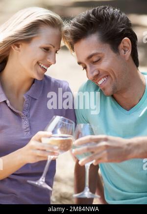 Auf die großen Erinnerungen. Nahaufnahme eines glücklichen jungen Paares, das draußen Wein trinkt. Stockfoto