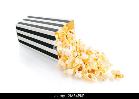 Leckeres Käsepopcorn, das aus einem schwarz gestreiften Eimer fällt, isoliert auf weißem Hintergrund. Streuung von Popcornkörnern. Filme, Kino und Ente Stockfoto