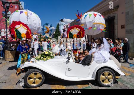 Eine Braut auf dem Rücken eines klassischen MG-Sportwagens auf einer Hochzeitsfeier auf der Straße in Oaxaca, Mexiko. Stockfoto