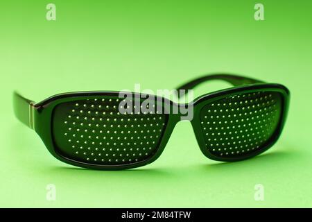 Schwarze perforierte medizinische Brille auf grünem Hintergrund Stockfoto