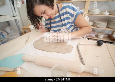 Brünette Frau, die Lehm im Kunsthandwerk modelliert. Hochwertiges Foto Stockfoto