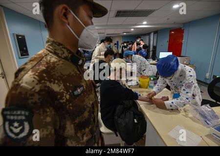 Fuyang, China. 12. Januar 2023. Eine Krankenschwester entnimmt einem jungen Mann Blut für ein paar Gesundheitschecks, bevor er ins Militär eingeliefert wird. Diese jungen Menschen wollen Soldaten werden, aber sie müssen sich strengen physischen und anderen Kontrollen unterziehen, bevor sie Soldaten werden können. Kredit: SOPA Images Limited/Alamy Live News Stockfoto