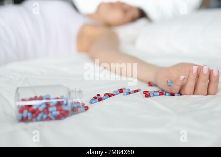 Uberdosis-Pillen und Drogenabhängige-Hintergrund. Die Frau schläft bewusstlos, nachdem sie Pillen auf dem Bett gegessen hat Stockfoto