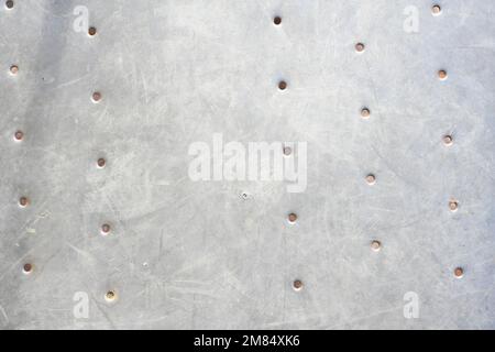Einfache graue Betonwand mit kleinen Löchern und subtiler Witterung, eine minimale industrielle Oberflächentextur und neutraler architektonischer Hintergrund Stockfoto