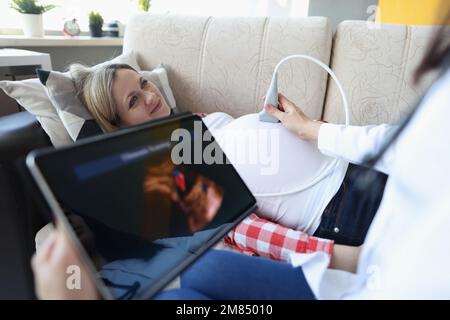 Gynäkologe führt Ultraschall bei Schwangeren zu Hause durch Stockfoto