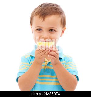 Gute Essgewohnheiten. Studioaufnahme eines Jungen, der eine orangefarbene Scheibe auf Weiß isst. Stockfoto