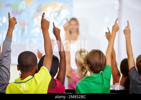 Begierige junge Köpfe, die bereit sind, alle Fragen ihrer Lehrer zu beantworten. Schulkinder heben während des Unterrichts die Hand, um eine Frage zu beantworten. Stockfoto