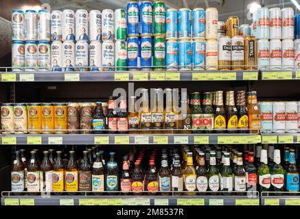 Flaschen mit vielen Biermarken auf den Regalen im Supermarkt. Stockfoto