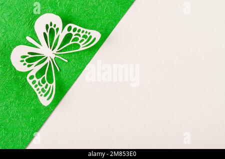 Schmetterling aus geschnitztem Papier oder Schnitt auf grünem und gelbem Hintergrund mit leerem Platz für Ihren Text oder Ihre Nachricht. Stockfoto