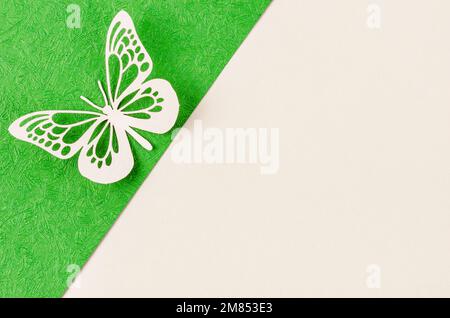 Ein Schmetterling aus geschnitztem Papier oder Schnitt auf grünem und gelbem Hintergrund mit leerem Platz für Ihren Text oder Ihre Nachricht. Stockfoto