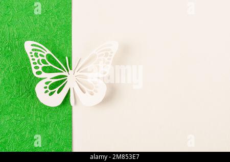 Schmetterling aus geschnitztem Papier oder Schnitt auf grünem und gelbem Hintergrund mit leerem Platz für Ihren Text oder Ihre Nachricht. Stockfoto